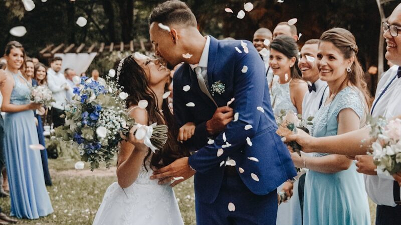 man in blue suit kissing woman in white wedding dress